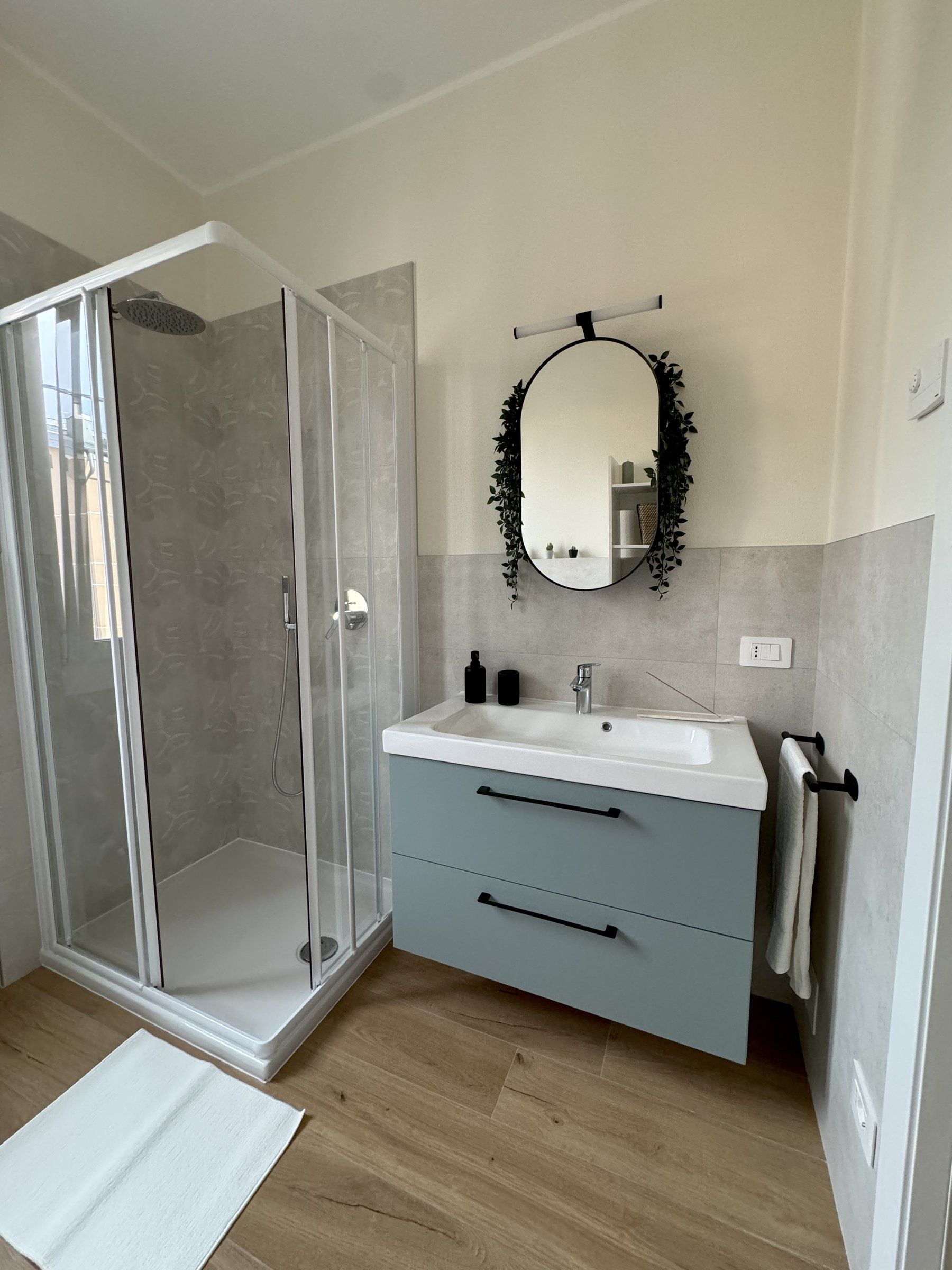 La doccia e il lavabo salvia con lo specchio ovale